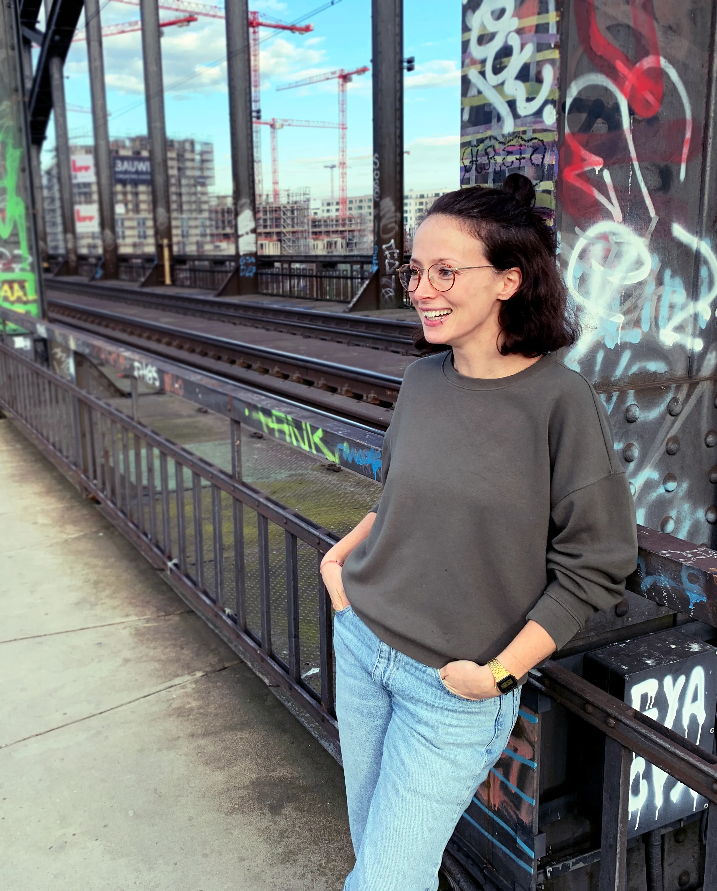 Ina steht auf der Deutschherrnbrücke in Frankfurt, angelehnt, Hände in den Hosentaschen und lacht. Sehr sympathisch ;)